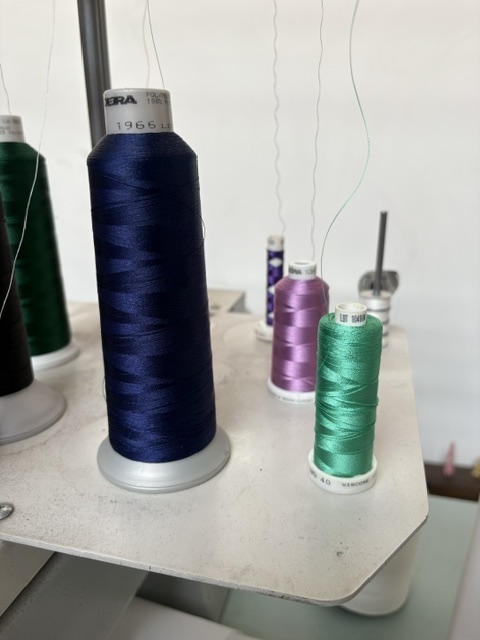 Cônes de fil de broderie installés sur la machine à broder — atelier Broderie Lévêque à Montreuil